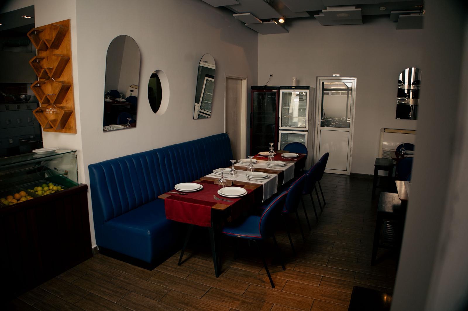 Divã azul e mesas postas na sala do Restaurante Kamilus