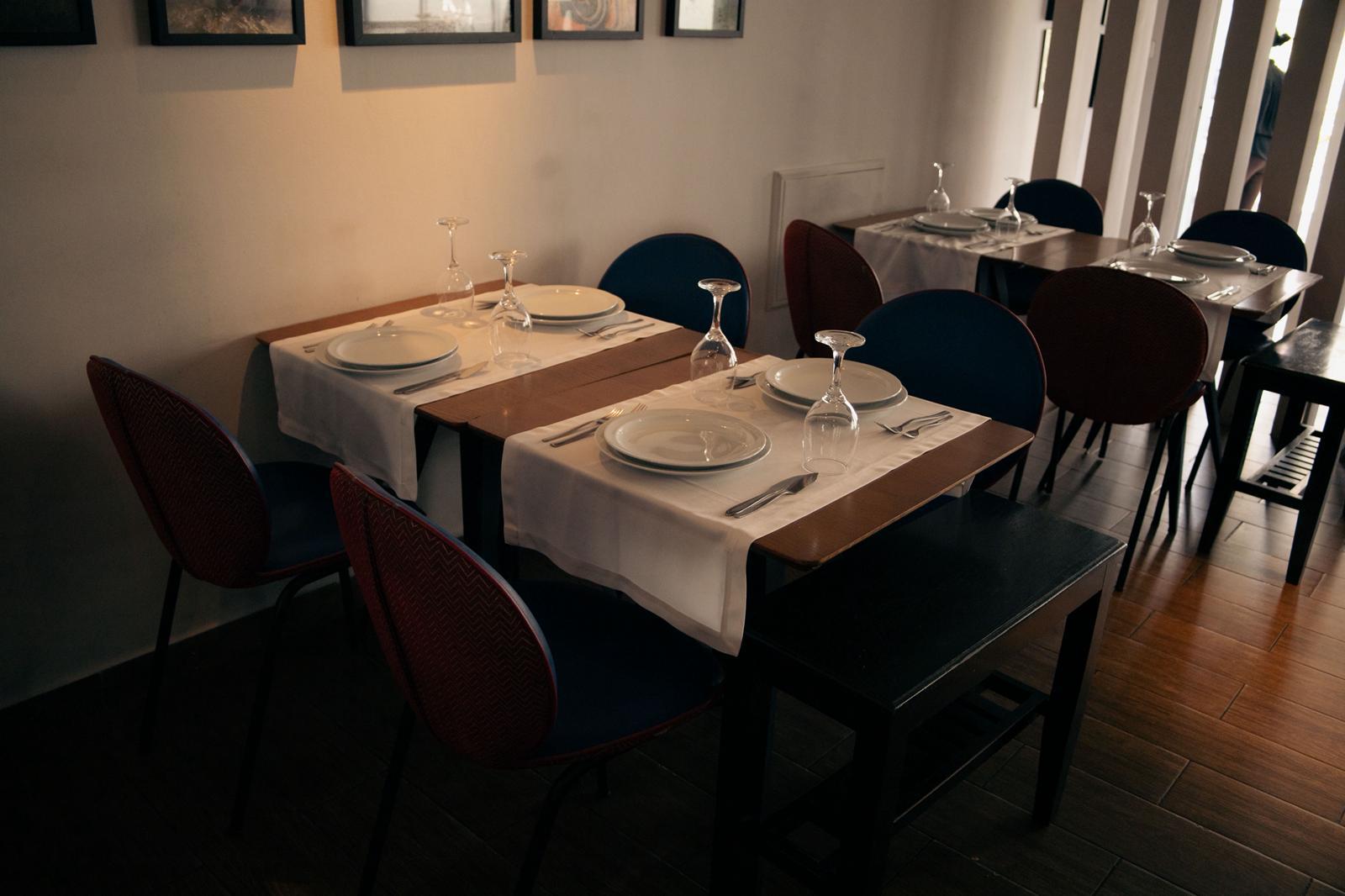 Detalhe de mesa posta com cadeiras de encosto encarnado